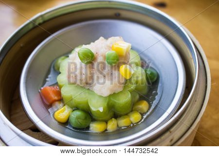 a kind of dimsum : momordica with pork pea and corn steamed on bamboo basket chinese stye