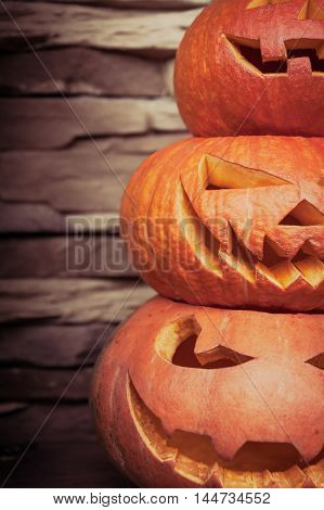 Stack of halloween jack o lanterns in vertical orientation on blurred stone background