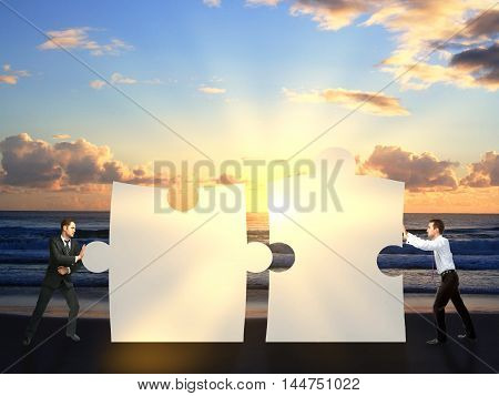 Two businessmen pushing puzzle pieces together on sea background with setting sun. Cooperation concept