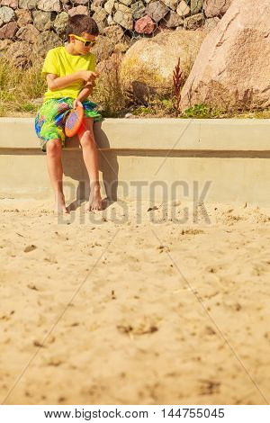 Play and fun concept. Little playful enjoyable boy kid throwing frisbee disc. Male child having fun playing outdoor on beach.