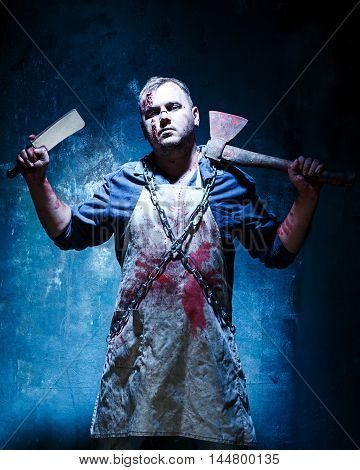 Bloody Halloween theme: crazy killer as bloody butcher with an ax on dark blue background