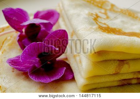 fresh hot blinis with violet flowers close up