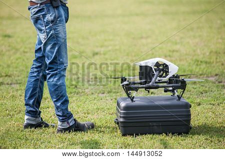 Drone on box near the men's feet on background of green grass