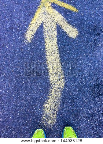 yellow arrow on the asphalt  a pair of running shoes