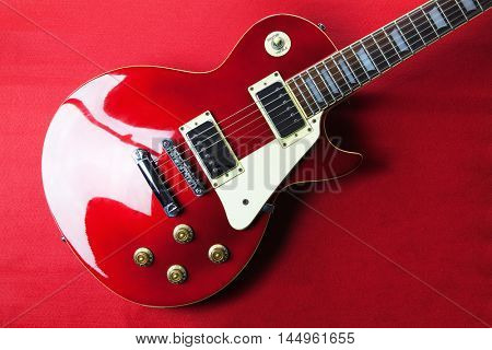 Deep red metallic solid body electric guitar on deep red background.