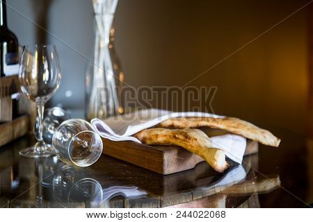 Shotis Puri - Traditional Georgian Bread. Bread Under A White Napkin. Two Glasses For Wine.