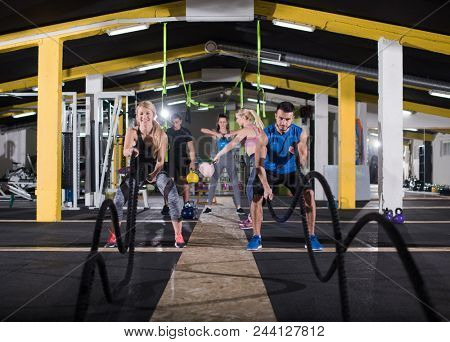 young fit sports couple working out in functional training gym doing  battle ropes cross fitness exercise
