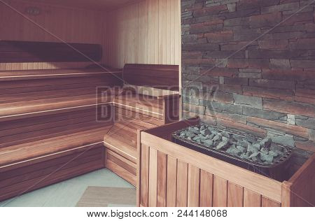 Wooden Bathhouse With A Heating Pot Filled With Stones, Close Up. Wooden Sauna Interior With Equipme