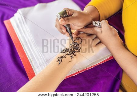 Woman Is Drawing On Hand. Draw On The Hand Indian Mehendi Picture.