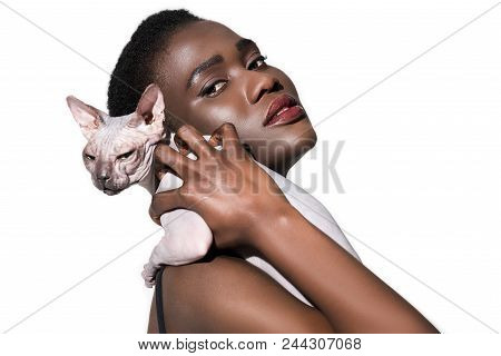 Attractive Young African American Woman Holding Sphynx Cat And Looking At Camera Isolated On White
