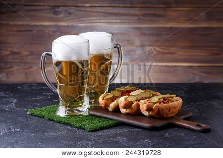 Photo Of Two Mugs Of Foam Beer, Green Grass With Football, Hotdogs On Wooden Board