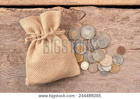 Pile Of Coins And Woolean Bag. Top View. Wooden Desk Background.