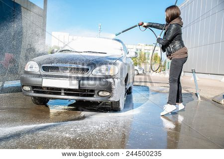 Young Woman Washing Car At Self-service Carwash