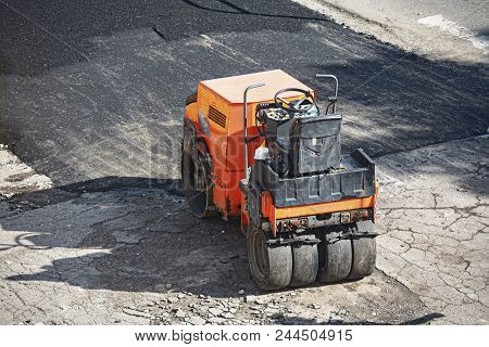 A Small Orange Light Machine For Laying A New Asphalt.