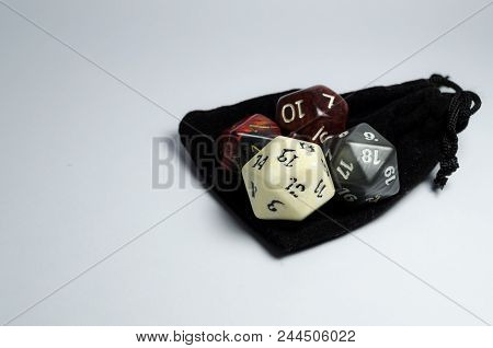 Some Rpg Dice Grouped Together On Top Of A Small Black Purse Isolated On A White Background. Dices O
