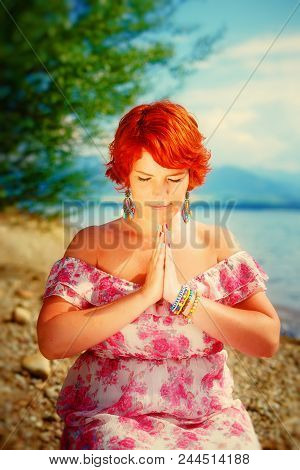 Beautiful Girl With Radiant Red Hair In Sommer Dress In A Meditative Spiritual Gesture Of Prayer