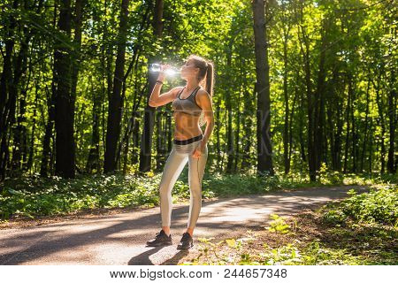 Young Woman Drinking Water After Running Outdoors.