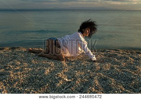 Fashion Photography By The Sea. Woman Stands On All Fours, Creeps On Beach In Evening. Girl Sexy, We
