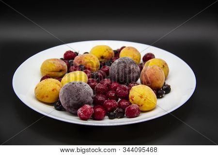 A Berry Mix From Frozen Currant, Apricot, Plum, Cherry On The White Plate. Frozen Berries From Freez