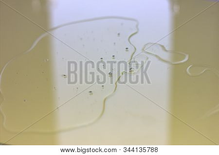 Liquid Transparent Gel Or Serum With Oxigen Bubbles On A Yellow Glass Surface. Hyaluronic Acid Or Se