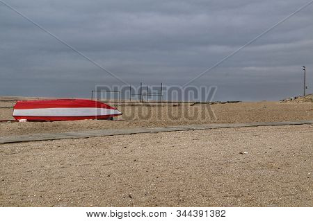 Red And White Fishing Boat Stranded On Aguda Beach In A Cloudy Day Of Winter