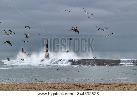 Giant Waves Breaking On The Breakwater And The Lighthouse On Aguda Beach, Miramar, Arcozelos Town