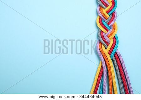 Top View Of Braided Colorful Ropes On Light Blue Background, Space For Text. Unity Concept