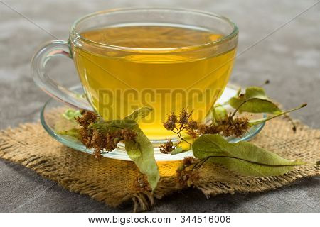 Glass Cup Of Tea From Linden Flowers On A Gray Background. The Concept Of Healthy Teas.