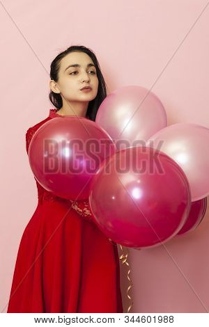 Young Pretty Woman In Red Evening Dress Holding Festive Air Balloons. Portrait Of Happy 20s Middle-e