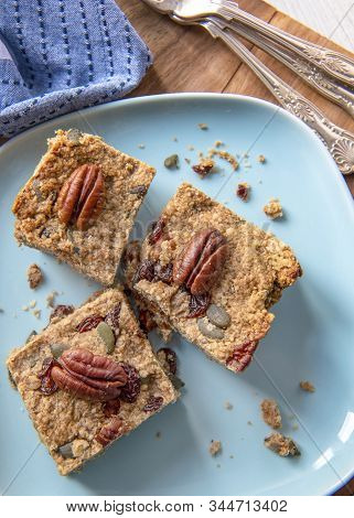 Plant Based  Vegan Cake ,recipe Filled With Nuts Fruit And Oats  Pieces Placed On A Blue Plate  Copy