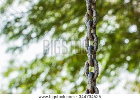 Iron Chain Object Hanging On A Blurred Unfocused Green Park Outdoor Natural Background With Bokeh Ef