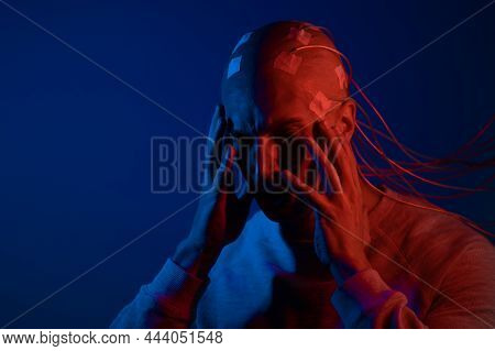 A Young Man With His Head Entangled In Wires, Clutched His Head, Electrical Contacts On His Bald Hea