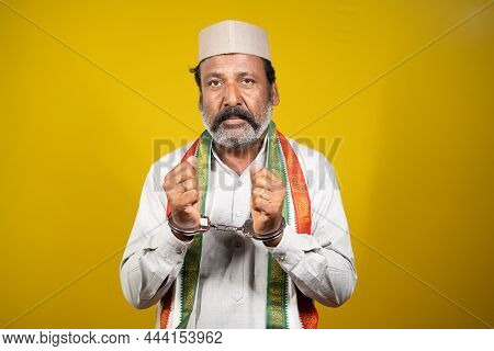 Worried Serious Criminal Politician With Hand Cuffs Looking At Camera On Yellow Background - Concept
