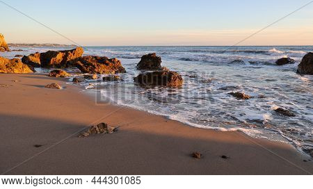 Malibu Waves At Sunset As The Sun Lights The Sand And Rocks Orange
