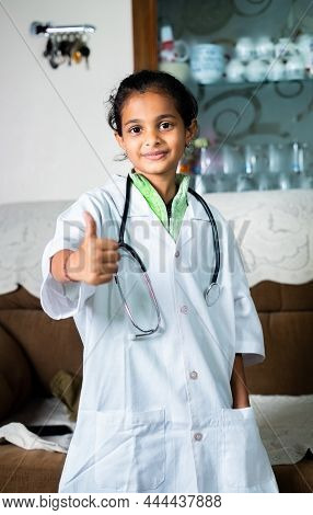 Portrait Shot Of Happy Smiling Girl With Doctor Dress And Stethoscope Showing Thumbs Up At Home - Co