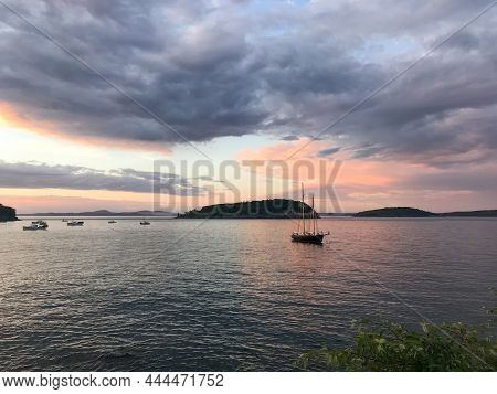 A Sailboat Rests In The Harbor Of Frenchman's Bay In Bar Harbor, Maine At Sunset With Clouds Rolling