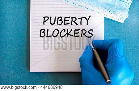 Medical And Puberty Blockers Symbol. Words 'puberty Blockers' On White Card. Doctor Hand In Blue Glo