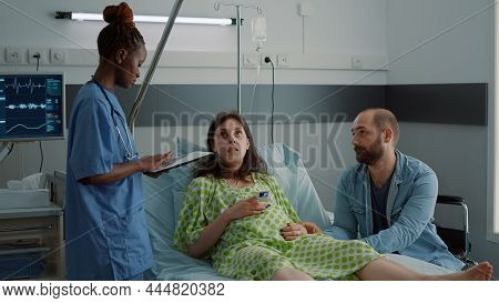 African American Nurse Using Tablet For Pregnant Patient Healthcare In Hospital Ward. Expecting Woma