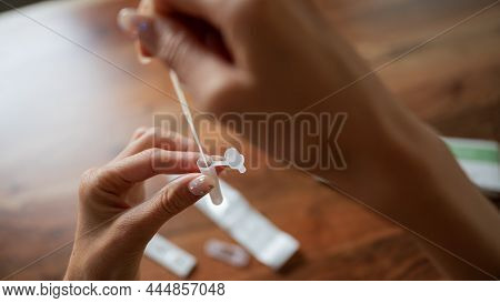 Closeup View Of Female Hand Placing Coronavirus Sample Stick Swab In A Saline Solution.