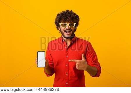 Happy Cheerful Beaded Man Pointing Finger At Smartphone With Empty Screen Looking At Camera With Too