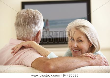 Senior Couple Watching Widescreen TV At Home