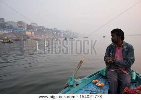 VARANASI, UTTAR PRADESH, INDIA - FEBRUARY 17, 2016 - Unidentified indian boatman on his boat on river Ganga at sunrise