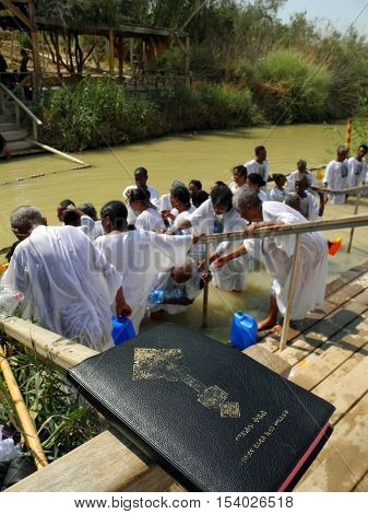 Bethabara Israel - August 23 2016: The Bible in the background of pilgrims from Ethiopia are dipped into sacred water of the Jordan River.
