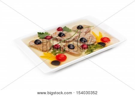 The jellied meat served on a white dish with segments of yellow sweet pepper, tomatoes, olives, parsley and leaves of the arugula isolated on a white background.