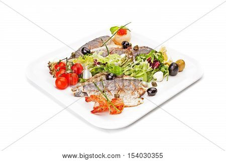Pieces of fish fillet, fried and served on a white dish, served by leaves of salad, with olives, cherry tomatoes, a mozzarella, arugula, a lemon segment, shrimps and tartlet with red caviar.