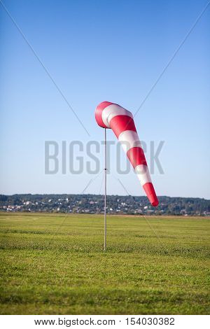 Windsock in a background of the green field and a grass at a light breeze.