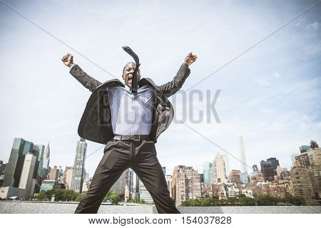 Confident happy businessman exulting and cityscape in the background