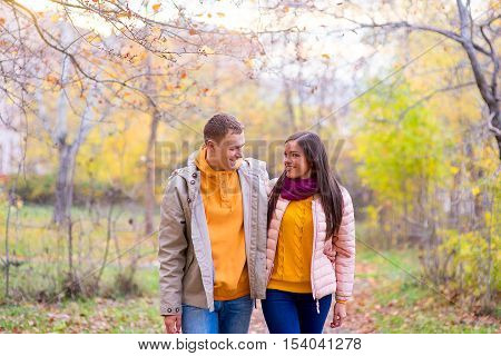smiling couple hugging in autumn park from front on the road between the trees