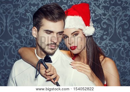 Sexy man in tuxedo with young santa lover holding whip portrait