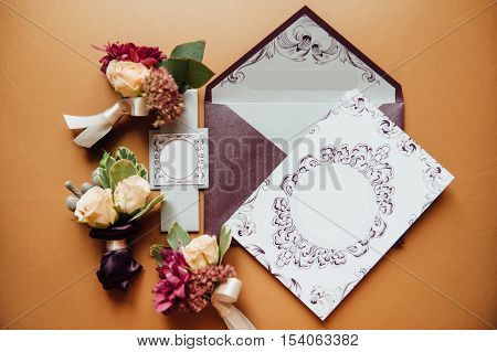 stylish envelope with invitation cards with boutonniere groom and his friends